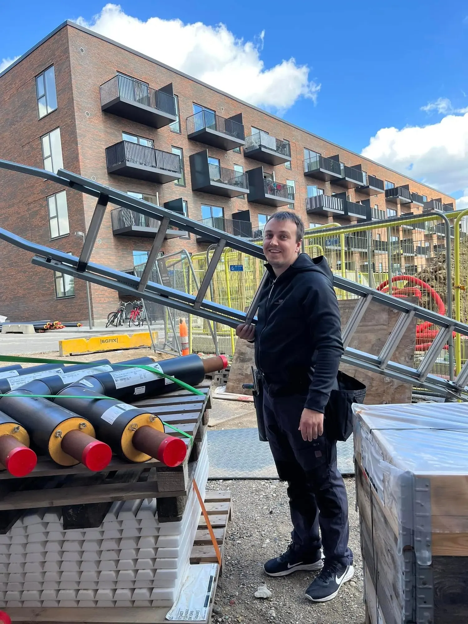 Benjamin fra BLS Vinduespuds ved sin stige foran en ny boligblok