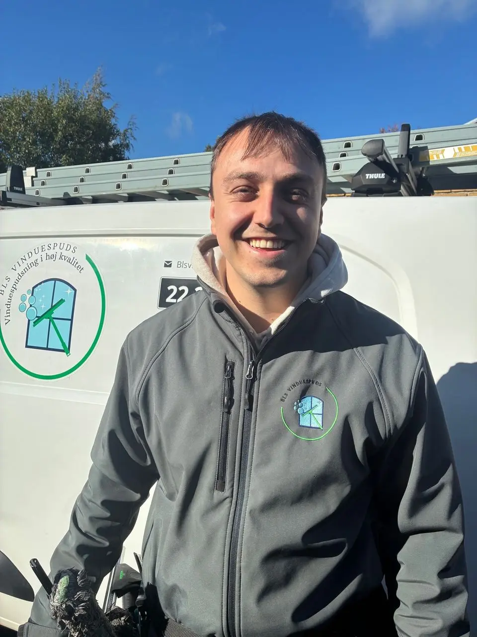 Benjamin Sahlgren smiler foran varevognen med BLS Vinduespuds' logo
