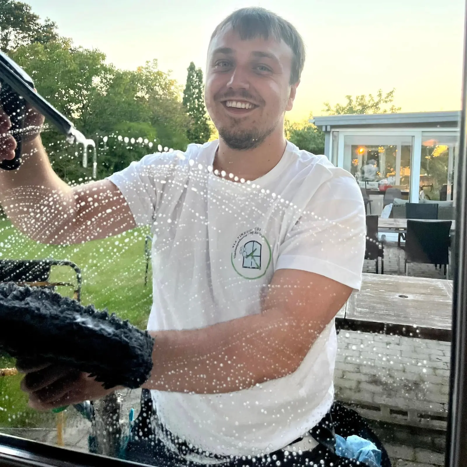 Benjamin smiler, mens han vasker en rude med sæbevand