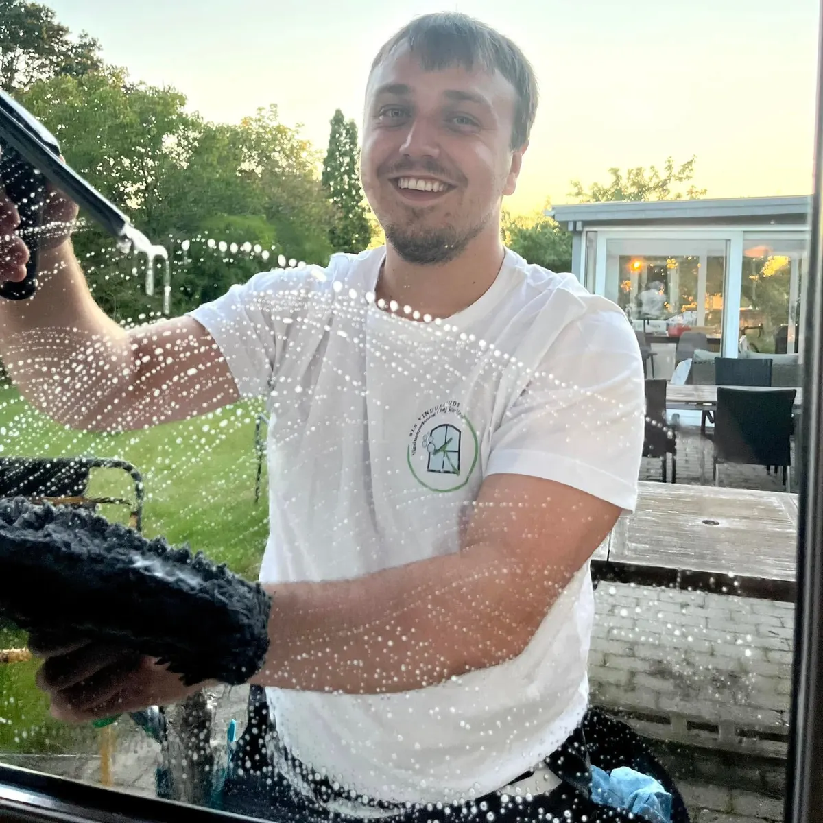 Benjamin smiler, mens han vasker en rude med sæbevand